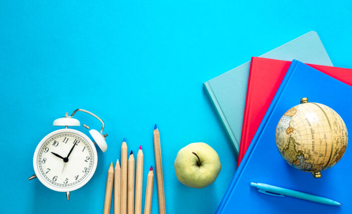 Flat lay background with colorful educational supplies on bright blue background, top view, back to school concept.